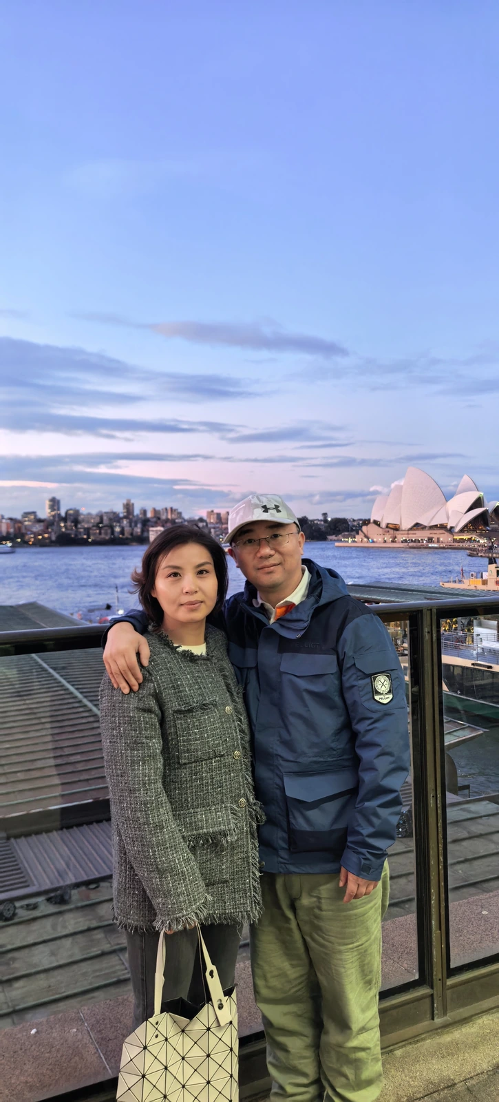 两人站在暮色中的海港栏杆旁